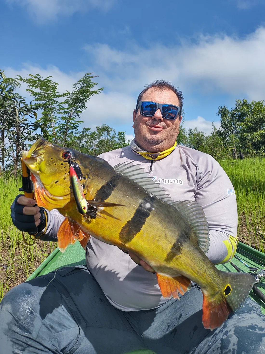 Pescador mostra um tucunaré em registro do acervo da HD Viagens