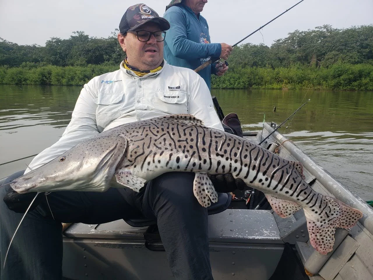 Pescador no barco mostra um grande peixe de couro