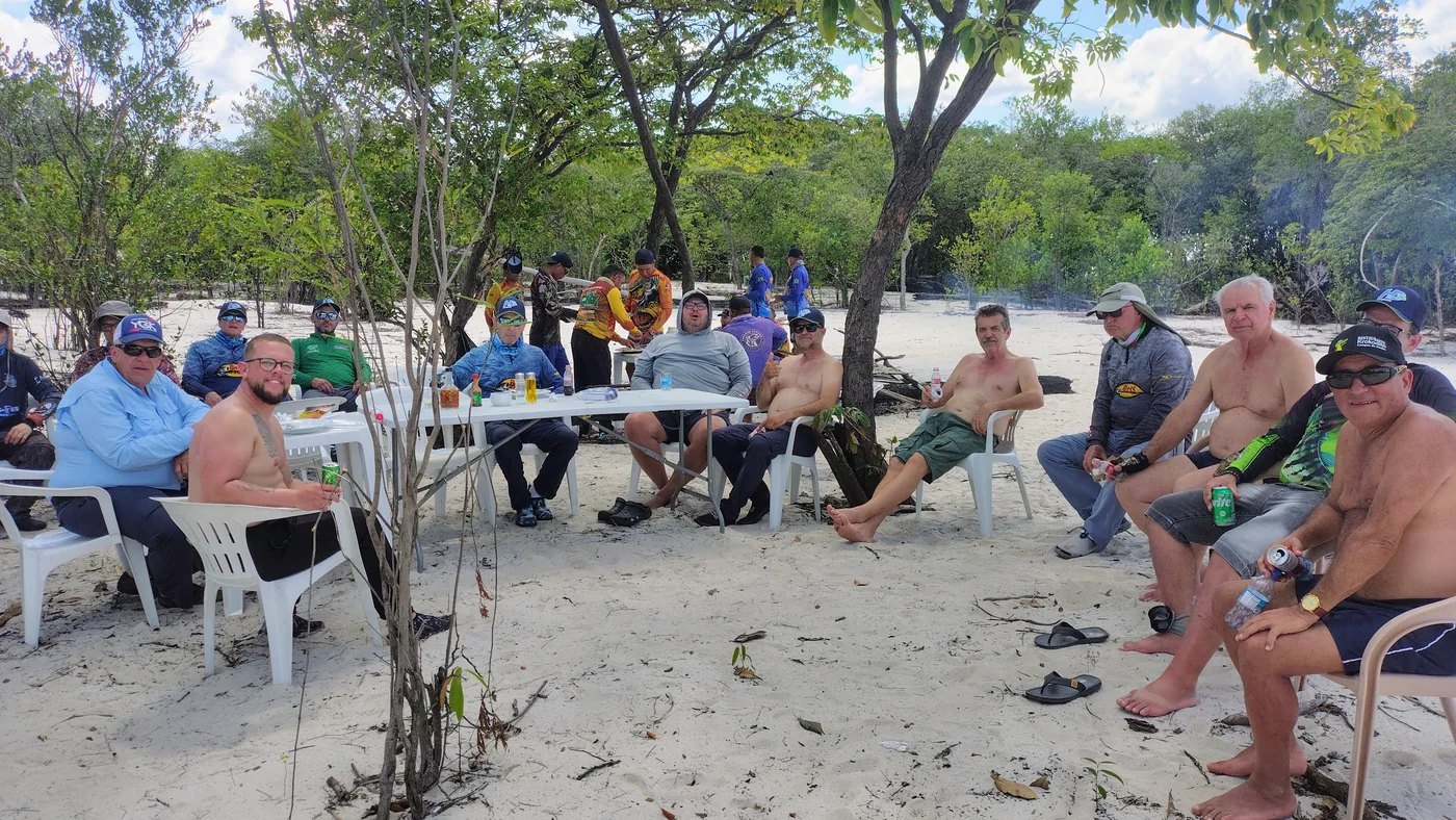 Grupo reunido para uma refeição à sombra das árvores, durante uma viagem