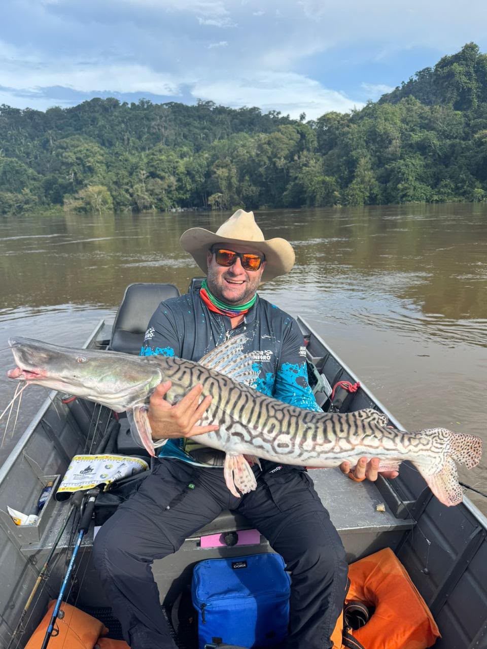 Pescador com peixe de couro em barco no Rio Apiacás